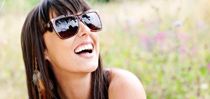 Woman in sunglasses smiling outdoors after teeth whitening in Schaumburg