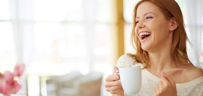 Laughing woman holding white coffee cup after dental bonding in Schaumburg