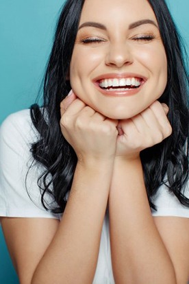 Woman smiling brightly and resting her chin on her hands