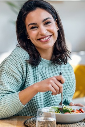a woman smiling while enjoying a healthy meal 