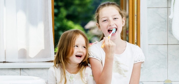 Two children brushing teeth after receiving dental sealants