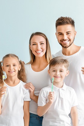 Happy family of five holding toothbrushes