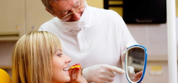 Dental patient looking at her smile in the mirror after gum disease treatment