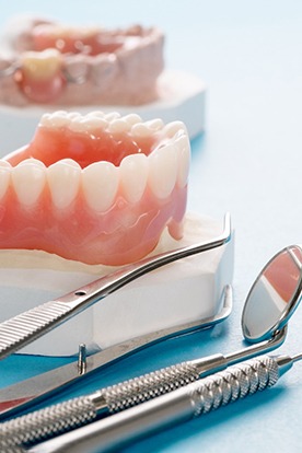 Dental tools lying next to model of dentures