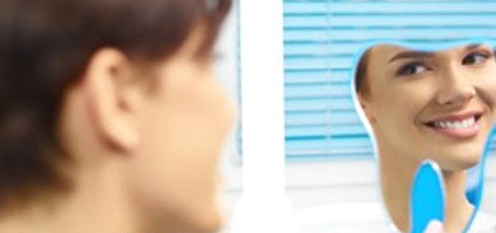 Woman looking in the mirror at her same-day crowns in Schaumburg