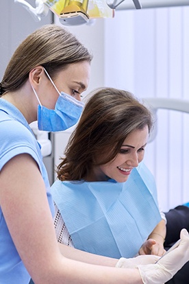 Dental assistant reviewing cost with smiling patient