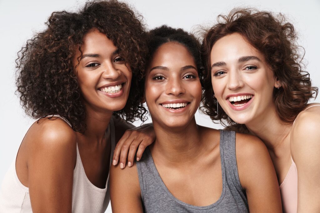 Three young women leaning on each other smiling